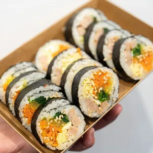 a hand holding a box of sushi