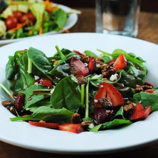 a plate of spinach salad and a glass of water