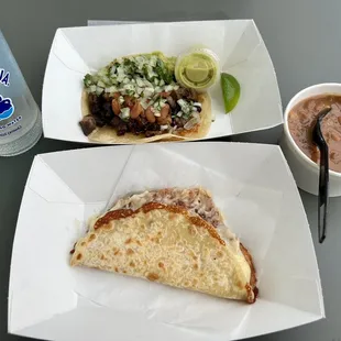 A Deluxe Beef Taco in the rear, a Quesadilla in front, and Beans on the side.