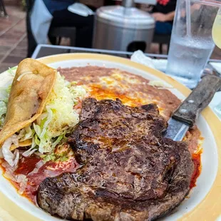 Rib eye (perfectly cooked) with a taco and enchilada.