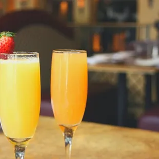 two glasses of orange juice and a strawberry