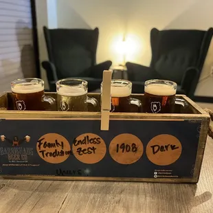 four glasses of beer in a wooden crate