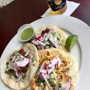two tacos and a beer on a table