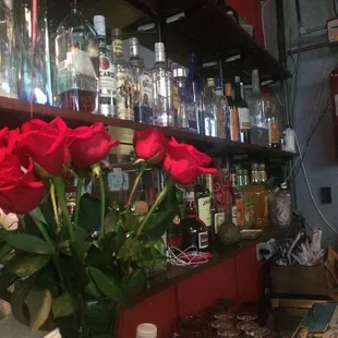 a vase of red roses on a bar