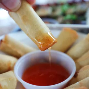 a person dipping sauce onto a plate of food