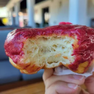 a hand holding a donut with a bite taken out of it