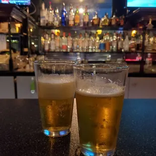 two glasses of beer on a bar