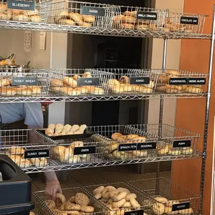a man standing in front of a rack of bagels
