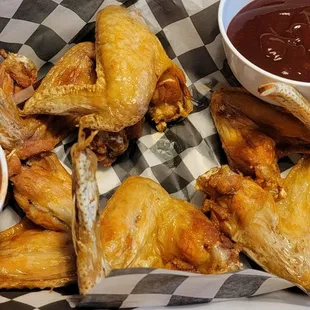 Chicken wings with hot and BBQ sauce on the side.