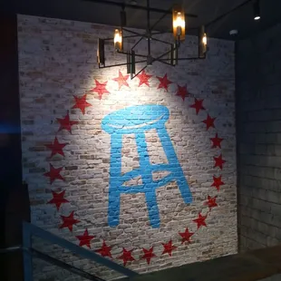 a brick wall with red stars and a blue stool