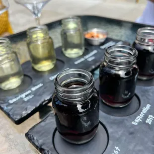 four jars of wine on a slate tray
