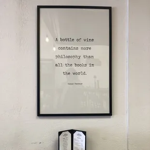 A sign with the quote "A bottle of wine contains more philosophy than all the books in the world." by Louis Pasteur