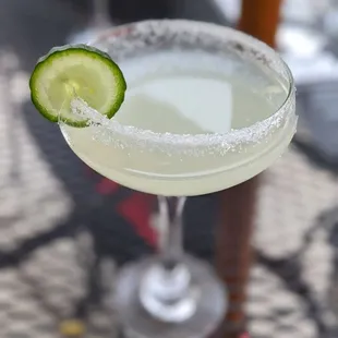 a close up of a margarita with a slice of cucumber on the rim