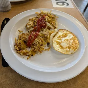Hash browns scattered with onions and 1 over medium egg.