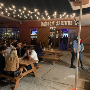 Rude owners at a table drinking beer telling employees to monitor customers too often.