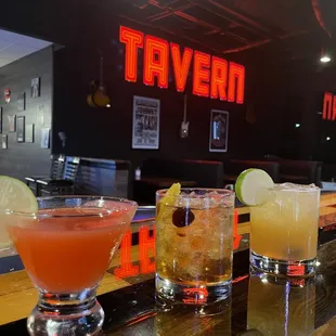 a row of cocktails on a bar