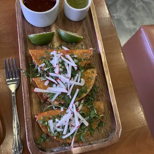a plate of nachos with salsa and lime wedges