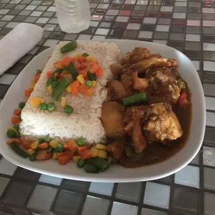 Juicy plate of white rice and curry chicken with some mixed veggies