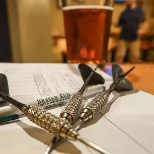 darts and a glass of beer on a table
