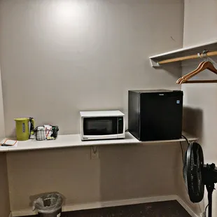 Little area outside of bathroom with fridge, microwave and things to make coffee