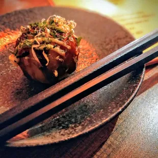 a close up of a dish with chopsticks