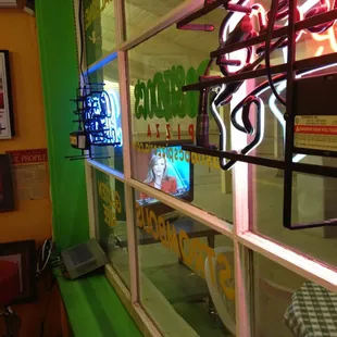 Looking outside from window. There's tables, chairs and A TV.