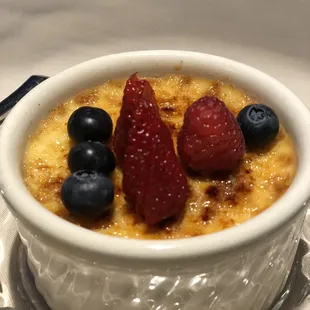 a bowl of creme with berries and blueberries