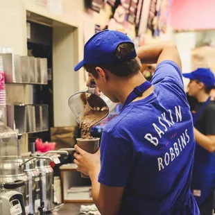 a man in a blue shirt and blue cap making ice cream