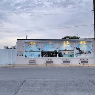 The side of the restaurant. The parking lot is at the back of the restaurant. There is outdoor seating in the back.