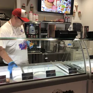 Server scooping ice cream, screen menu with pricing up above