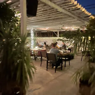 people sitting at a table under a pergol roof