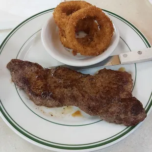 Boneless New York strip steak with onion rings and coleslaw as sides