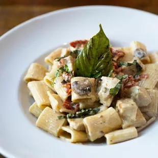 a plate of pasta with mushrooms, spinach and basil