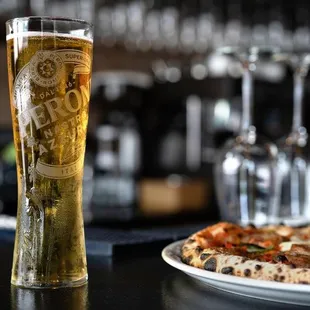 a glass of beer and a plate of pizza