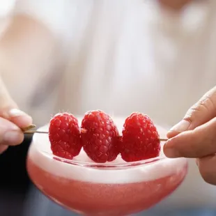 a person holding a spoon with raspberries in it
