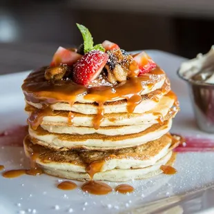 a stack of pancakes with syrup and strawberries