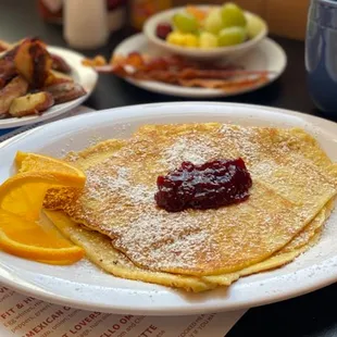 a plate of pancakes and fruit on a table
