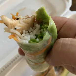 a hand holding a sandwich with rice and vegetables