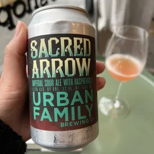 a hand holding a can of sacred arrow