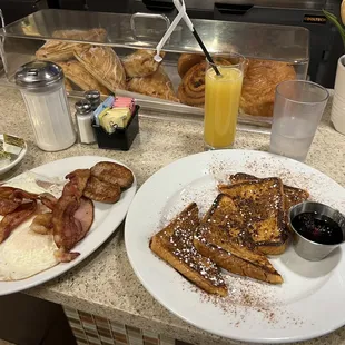 a breakfast of french toast, bacon, eggs, and bacon