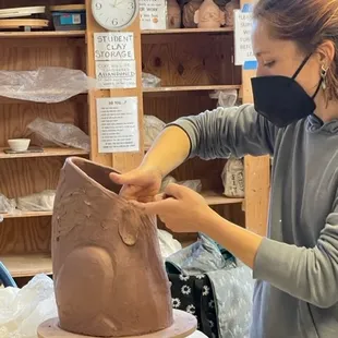 Instructor Katherine Maloney adds texture to her animal sculpture.
