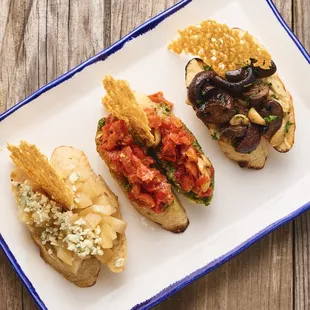 Bruschetta three ways comes with (1) roasted tomato &amp; pesto, (2) pear, blue cheese &amp; local honey and (3) mushroom, hummus &amp; parmesan cheese.