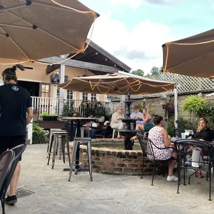 a group of people sitting at tables under umbrellas