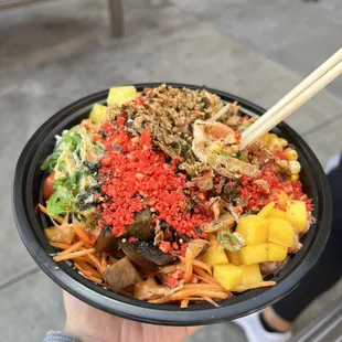 a person holding a bowl of food with chopsticks