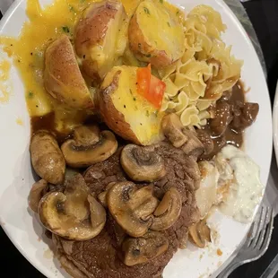 a plate of meat, potatoes, and mushrooms