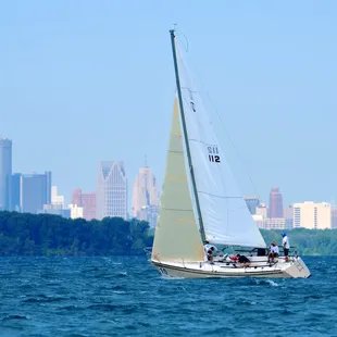 a sailboat in the water with a city in the background