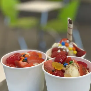 two cups of ice cream with fruit and candy