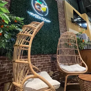 two wicker chairs in front of a brick wall