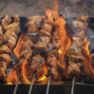 skewers of meat being cooked on a grill