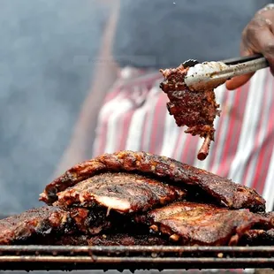 a man cooking ribs on a grill